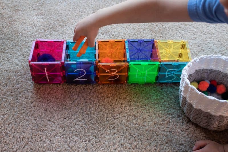Magnetic Tile boxes with the numbers 1-5 written on them. Used to count pompoms into the box.