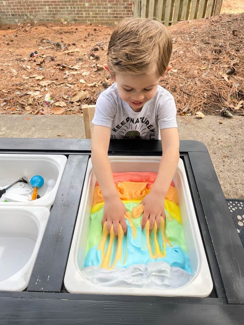Child playing with rainbow sensory activity.
