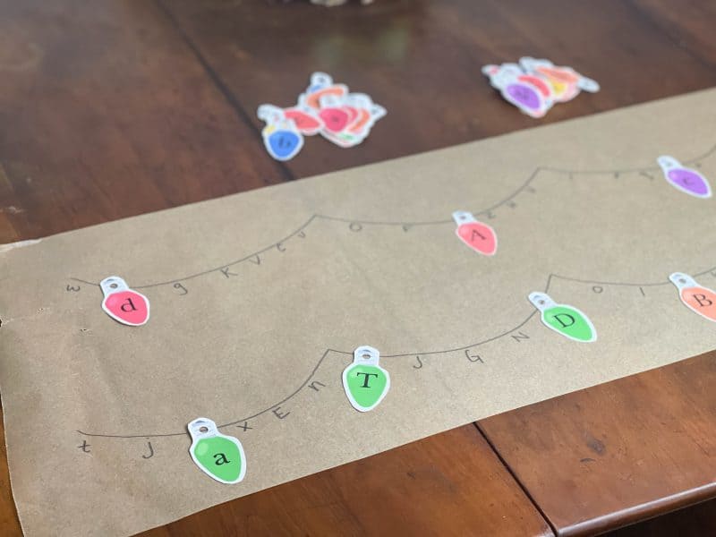 Match the Christmas Lights Activity.Brown parchment paper with the alphabet written on it. Paper Christmas lights with alphabet matching the letters.