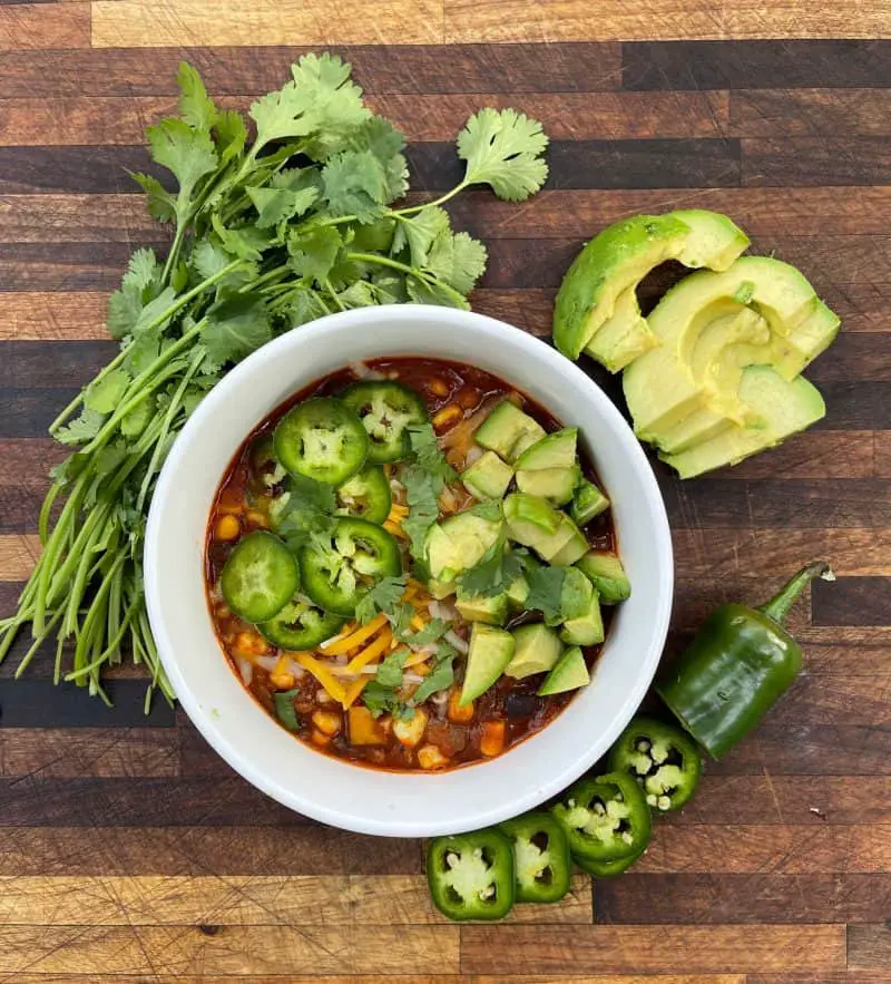 Slow Cooker Chili topped with cheese, avocado, and jalapeños