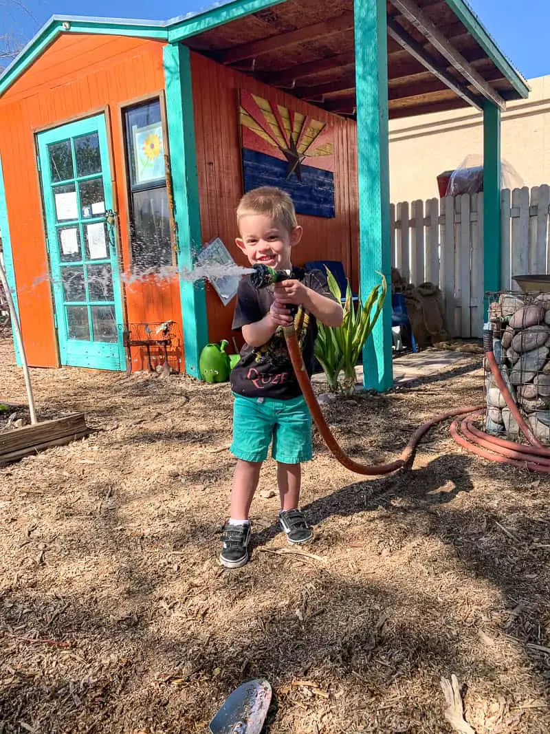 Toddler spraying hose in garden